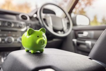 Vibrant green piggy bank on the dashboard, symbolizing affordable and economical car rental services in Kuala Lumpur, for budget-friendly travel.
